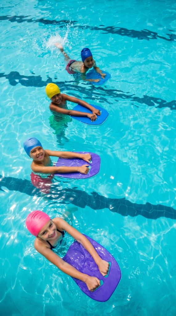 Niños practicando desplazamiento acuático con tablas en piscina